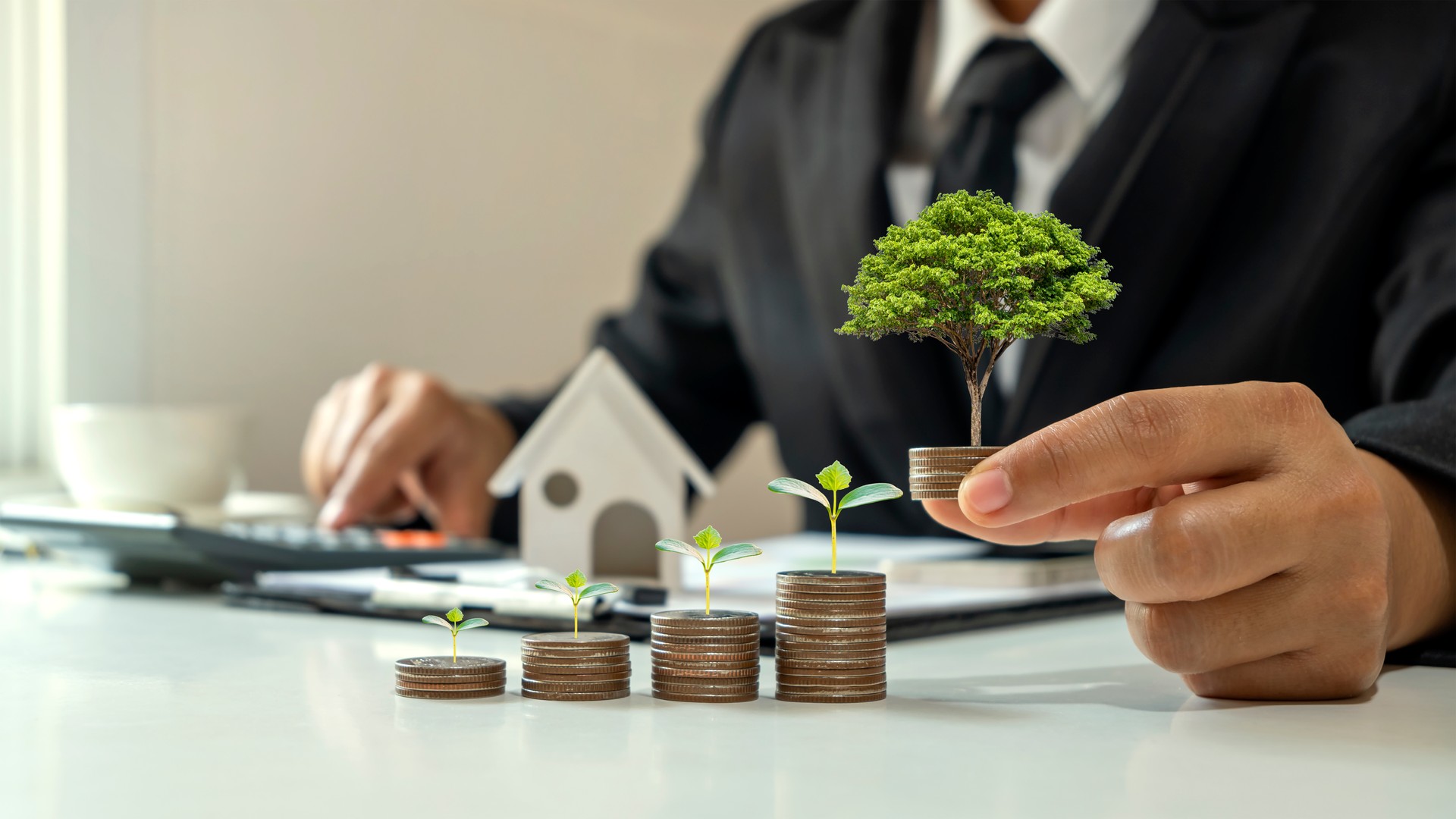 Businessman holding a coin with a tree growing on coins and a tree growing on stacked coins, business growth concept, finance, investments